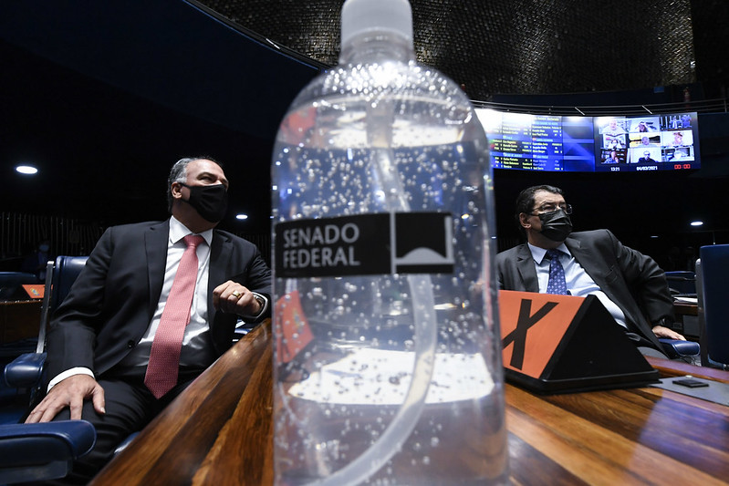 CPI da Covid. Cuidado com a pandemia. Fernando Bezerra e Eduardo Braga separados por frasco de álcool em gel na votação da PEC Emergencial