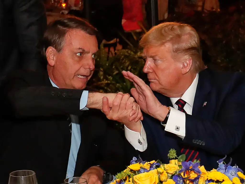 Donald Trump segura a mão de Jair Bolsonaro